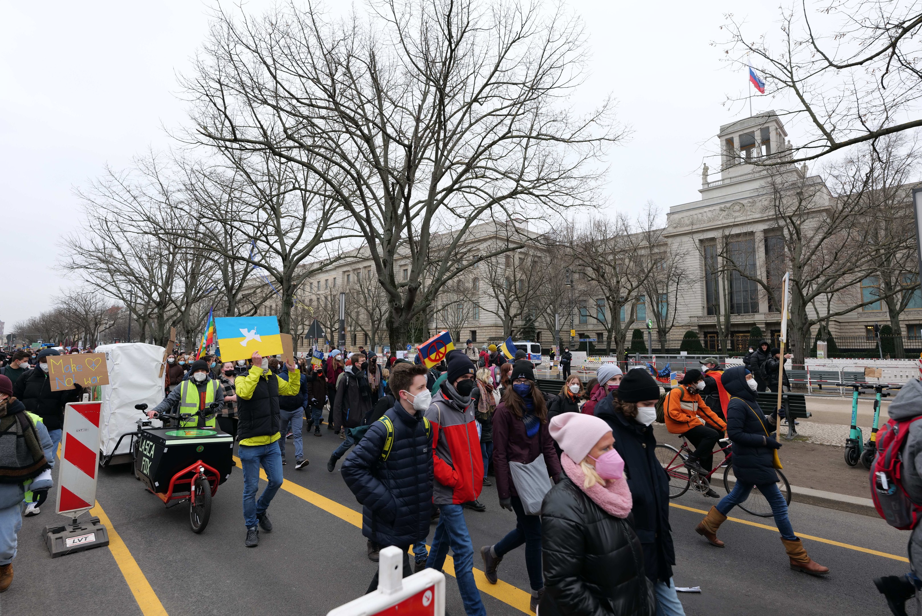 Eine große Gruppe von Menschen marschiert auf einer Straße in Washington, D.C. am 21. Januar 2020 mit Schildern, fahrradfahrend, mit Bäumen und einem klaren blauen Himmel im Hintergrund.