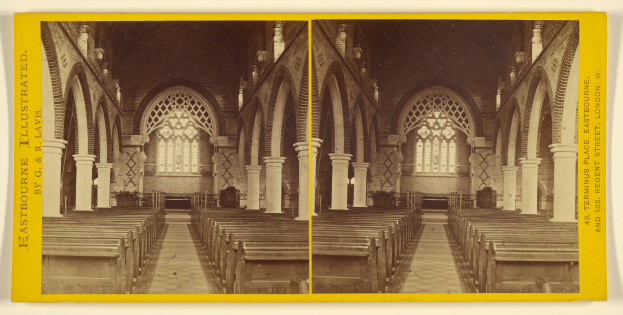 Ein altes Foto einer Kircheninnenseite mit hölzernen Kirchenbänken, Säulen, Bögen und Buntglasfenstern, das detaillierte Wanddesigns, einen gemusterten Teppich auf dem Boden und sichtbaren Text an den Wänden zeigt.