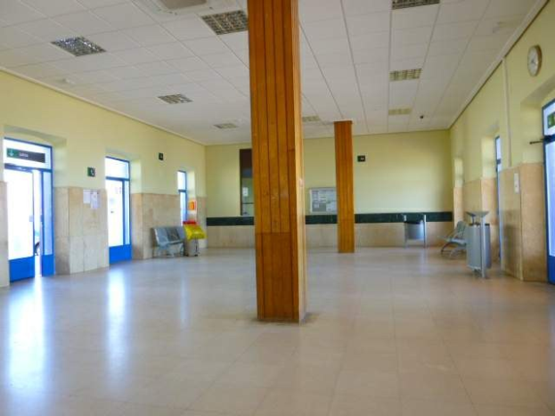 Großer Büroraum mit zahlreichen Fenstern, Türen, Säulen, Stühlen, Mülltonnen, einer Wanduhr und Deckenleuchten zur Miete in einer City-Lage.