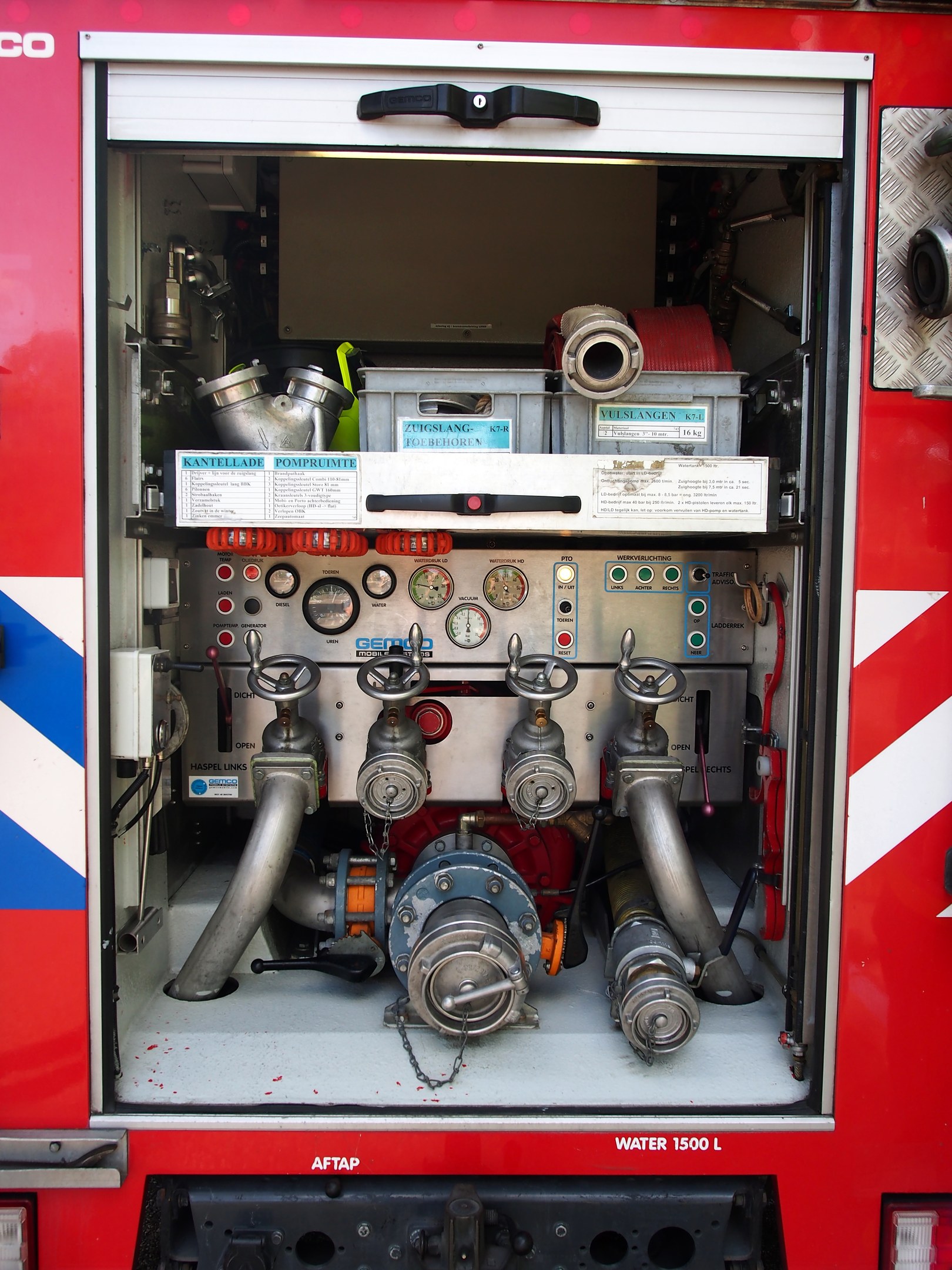 Roter Feuerwehrauto mit offener Tür, die den Motorraum mit Rohren, Messgeräten und anderen Komponenten enthüllt.