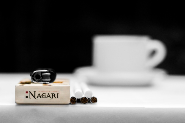 Ein Tisch mit einer Tasse und Untertasse, Zigaretten, Müll und einer Schachtel.