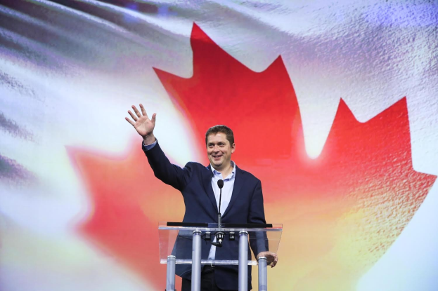 Premierminister Alex Salmond spricht an einem Rednerpult mit Mikrofonen vor einer kanadischen Flagge, mit einem Bildschirm im Hintergrund.