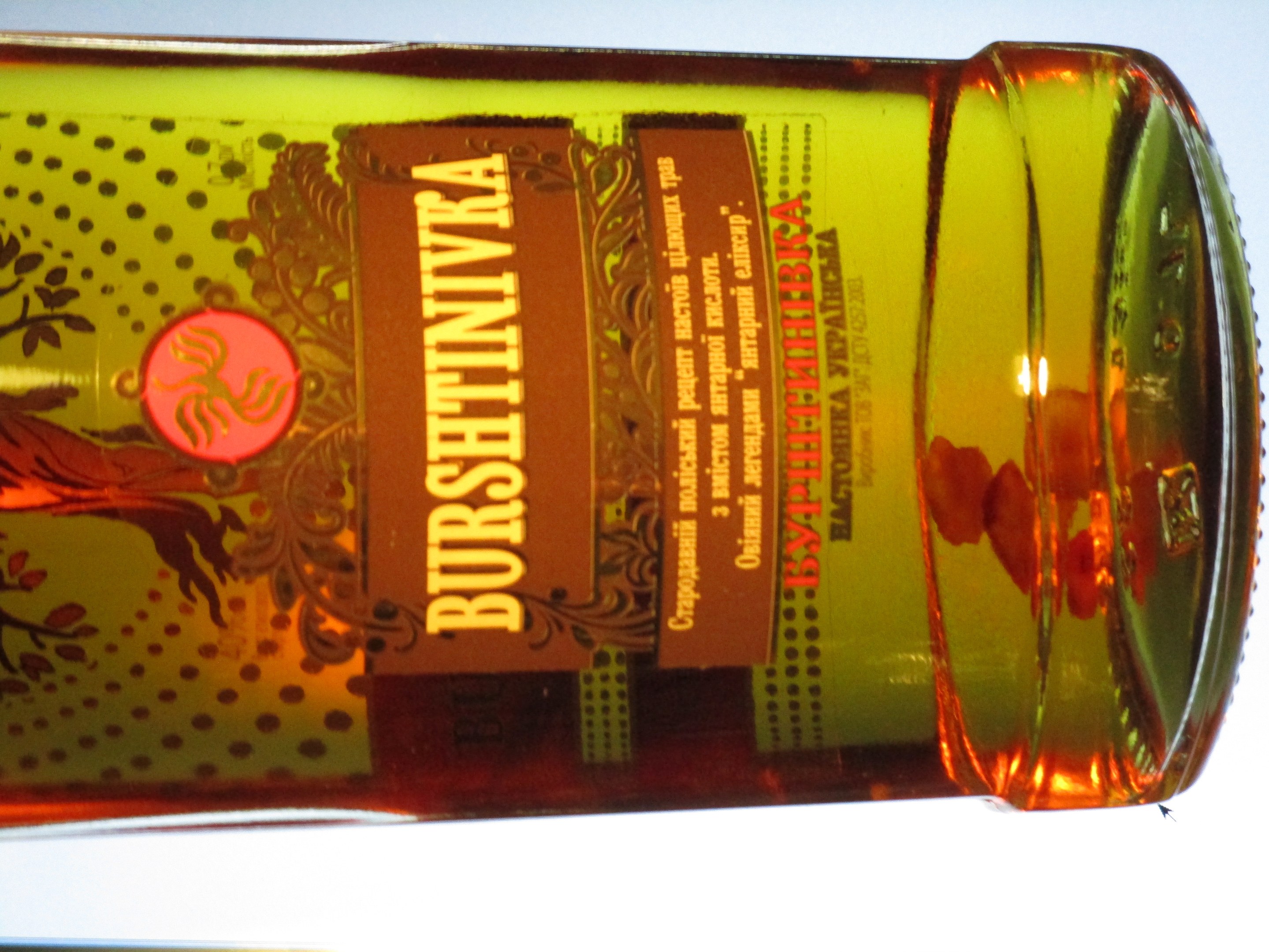 Eine Flasche Olivenöl mit einer goldbraunen Flüssigkeit und einem Etikett steht auf einem Tisch.