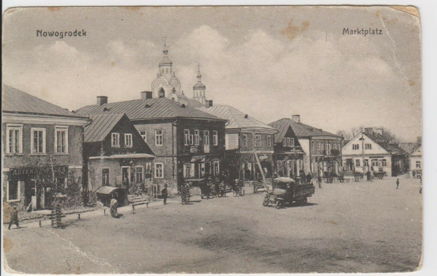 Schwarz-weiß-Foto des Marktplatzes in Nowogrodziec, Deutschland mit Gebäuden, Menschen, Karren, Pfählen, Bäumen und Himmel, beschriftet mit "Marktplatz in Nowogrodeek, Deutschland".