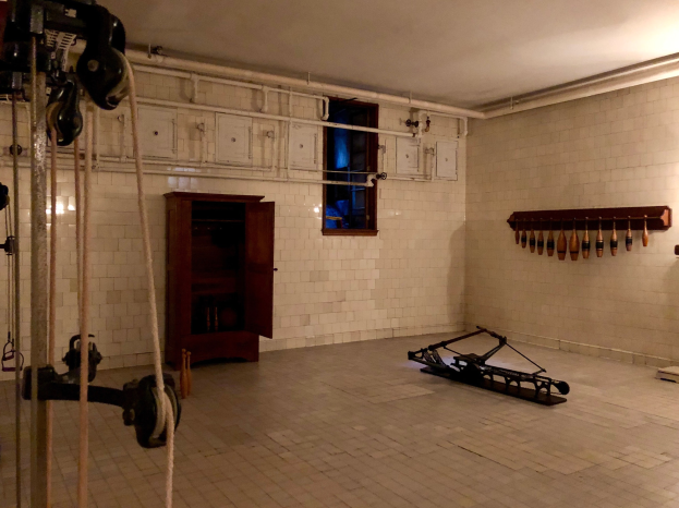 Ein unordentlicher Raum im ehemaligen Gefängnis St. Louis mit Seilen, Maschinen und anderem Equipment, mit einem Schrank, Fenster und Deckenlampe.