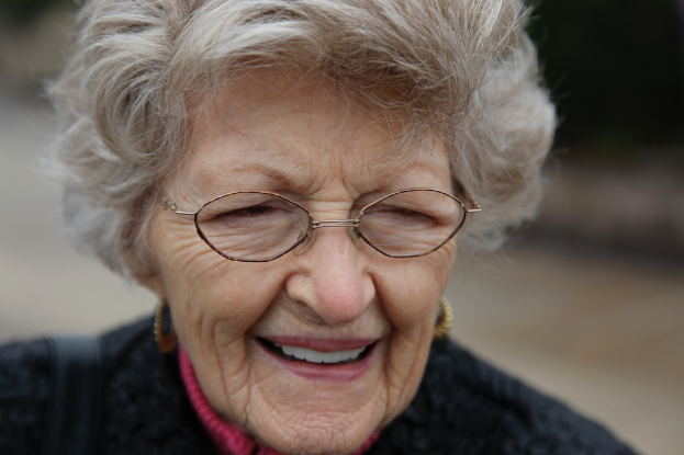 Eine Frau mit Brille lächelt vor einem unscharfen Hintergrund.