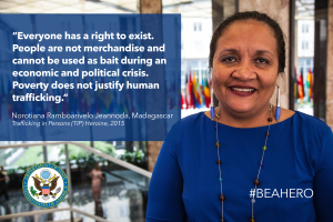 Eine Frau in einem blauen Kleid steht lächelnd vor einem Gebäude mit einem Zitat über Menschenrechte, umgeben von Menschen, Pflanzen und Flaggen, und einem Logo und Text auf der linken Seite.