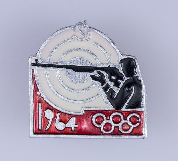 Olympisches Emblem mit einem Mann in rot-weiß gestreiftem Hemd und schwarzem Hut, der ein Gewehr auf ein Ziel richtet, mit dem Text "1964 Olympische Spiele", vor einem hellblauen Himmel mit weißen Wolken.