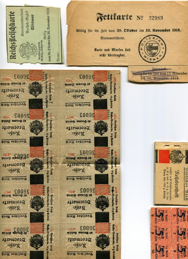 Sammlung von abgenutzten, alten deutschen Tickets und Briefmarken auf einem weißen Hintergrund, einige mit gedrucktem Text und Zahlen.