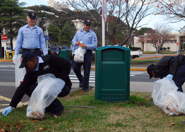 Drei Polizisten in Uniform sammeln Müll an einer Straßenrand