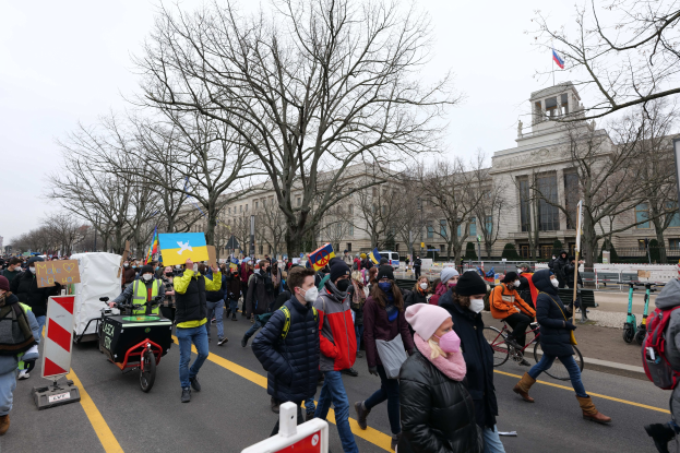 Eine große Gruppe von Menschen marschiert auf einer Straße in Washington, D.C. am 21. Januar 2020, mit Schildern und Fahrrädern, mit Bäumen und einem Gebäude im Hintergrund bei klarem blauem Himmel.