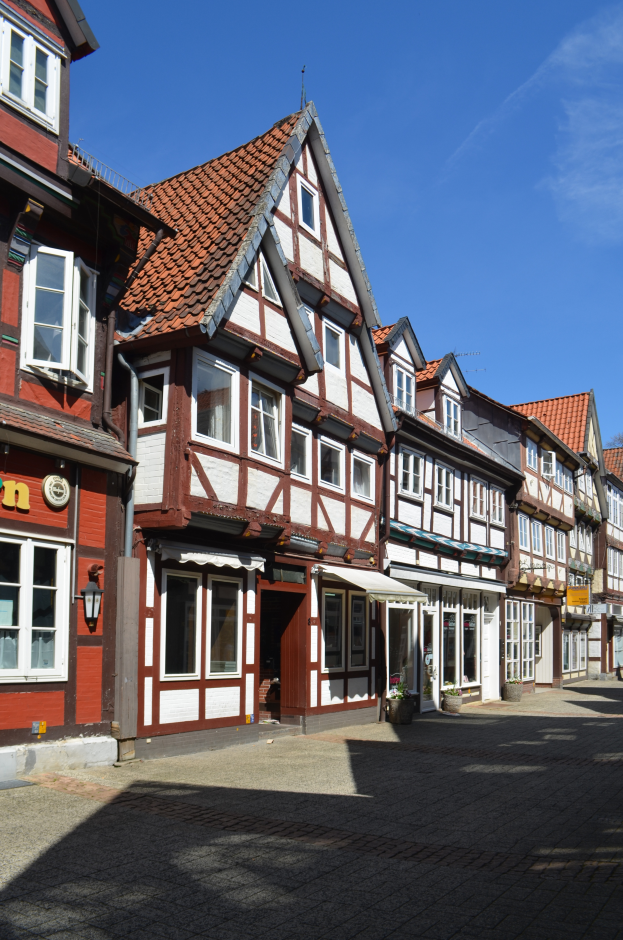Ein Kopfsteinpflasterweg in Heidelbergs Altstadt mit Gebäuden im Vordergrund, einem klaren blauen Himmel im Hintergrund und einer Laterne, die die Straße auf der linken Seite beleuchtet.