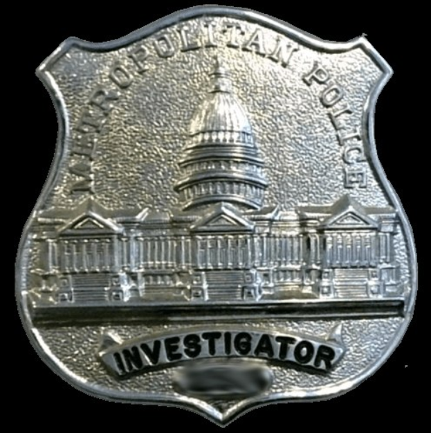Silbernes Polizei-Detektivabzeichen mit "Detektiv"-Text auf einem weißen Hintergrund.