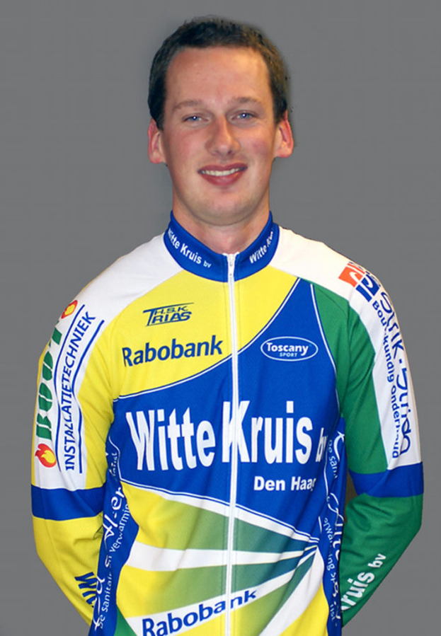 Ein Sportler posiert für ein Foto, trägt ein T-Shirt mit verschiedenen Sponsorennamen.
