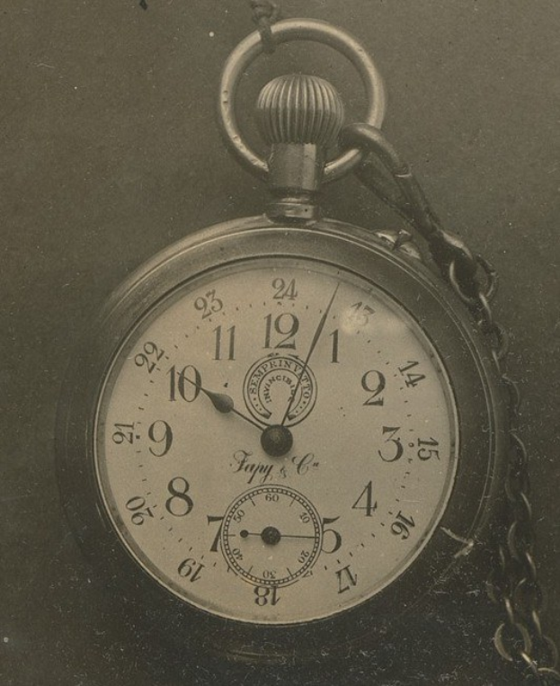 Altes Schwarz-Weiß-Foto einer Taschenuhr mit Kette, das eine nummerierte Ziffernblende zeigt.