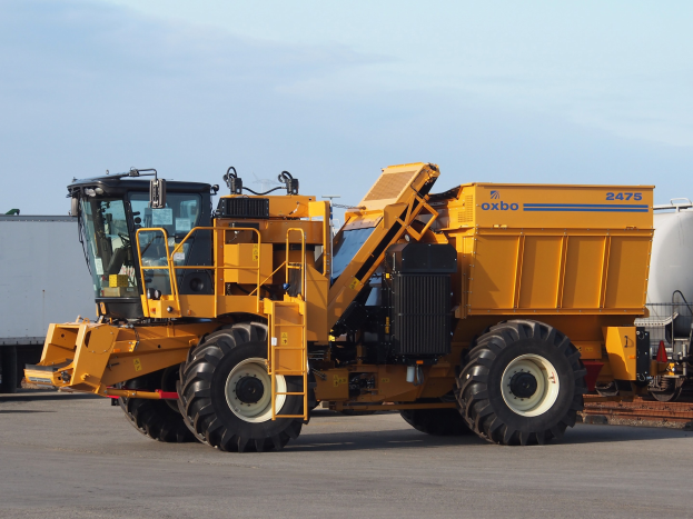 Ein großer gelber Radlader vor einem weißen Container auf einer Straße mit einem klaren blauen Himmel im Hintergrund