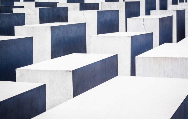 Eine große Anzahl von rechteckigen Betonplatten in verschiedenen Höhen, die in einem Gittermuster auf einem geneigten Feld angeordnet sind, mit einer bedrückenden Atmosphäre.