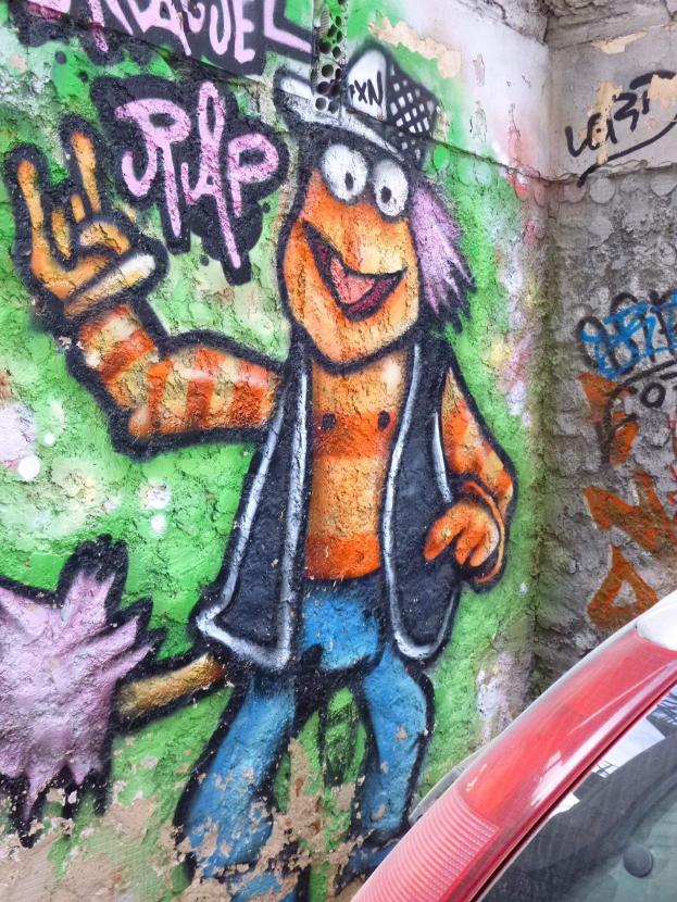 Ein rotes Auto, das vor einer Wand mit buntem Graffiti geparkt ist.