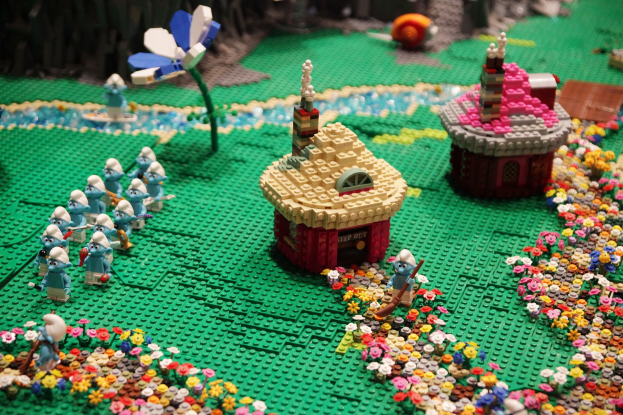 Ein Lego-Modell einer Kleinstadt mit Blumen, Spielzeug, Häusern, Pflanzen und anderen Gegenständen, mit einem leicht unscharfen Hintergrund.