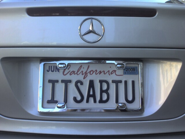 Ein graues Auto mit einem Mercedes-Benz-Emblem und einem Kennzeichen mit Text.