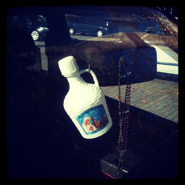 Ein Auto steht mit einer Kette und einer Flasche daneben auf dem Straßenrand.