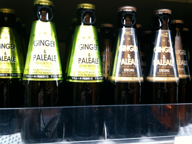 Mehrere braune Alkoholflaschen mit grünen und braunen Etiketten, einige mit Öffnerkapseln, auf einer Glasfläche platziert.