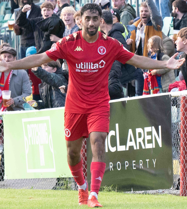 Ein Fußballer in roter Uniform rennt mit ausgebreiteten Armen auf einem Feld, im Hintergrund eine Zuschauermenge und ein Banner mit der Aufschrift "Middlesbrough FC v Swansea City - Sky Bet Championship".