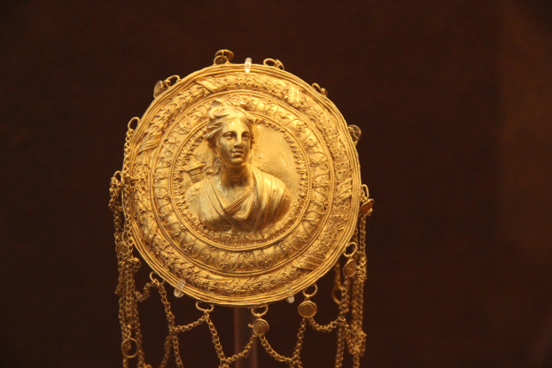 Goldene Medaille mit einer Frauengestalt auf dunklem Hintergrund, mit feiner Verzierung und königlichem Appear.