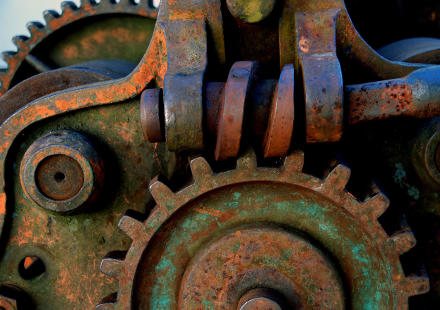 Ein Nahaufnahme eines verrosteten Metallzahnrads mit mehreren Zähnen und einem unscharfen Hintergrund.