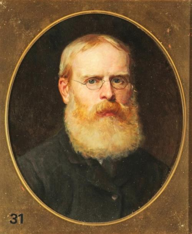 Portrait eines bärtigen Mannes in einem weißen Hemd und dunklen Hosen, der mit verschränkten Händen dasitzt, einen ernsten Gesichtsausdruck hat und konzentriert in die Ferne schaut, mit Zahlen links im Rahmen.