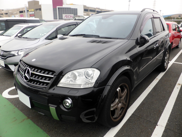 Schwarzer Mercedes-Benz ML 350 CDI Blueefficiency auf einem Parkplatz mit Gebäuden, Polen, Bäumen und einem klaren blauen Himmel geparkt.