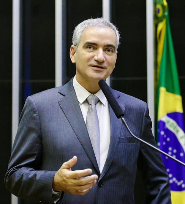 Ein Mann in Anzug und Krawatte spricht an einem Podium mit Mikrofon, brasilianische Flagge sichtbar im Hintergrund, wahrscheinlich über die Suspendierung von Präsident Michel Temer.