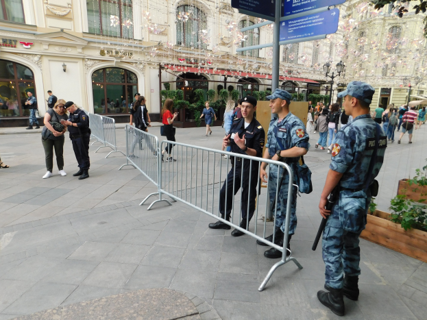 Polizeibeamte in Uniform hinter Absperrungen vor einer Menge stehend, einige mit Waffen, mit Gebäuden und Bäumen im Hintergrund während eines Einsatzes in Wien.