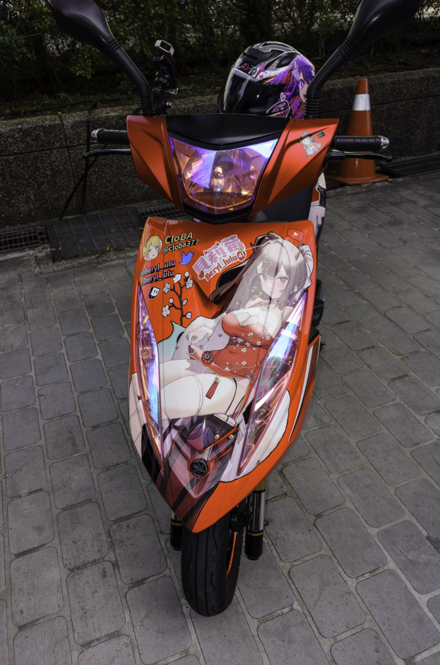 Oranger Roller auf der Straße mit Helm darauf geparkt, Verkehrskegel und Bäume im Hintergrund.