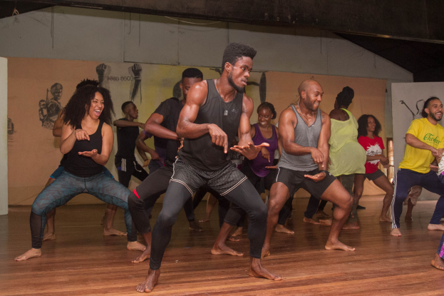 Eine Gruppe von Menschen tanzt in einem Choreografie-Kurs an der Universität Chicago, mit Wandgemälden und einer Decke über ihnen.