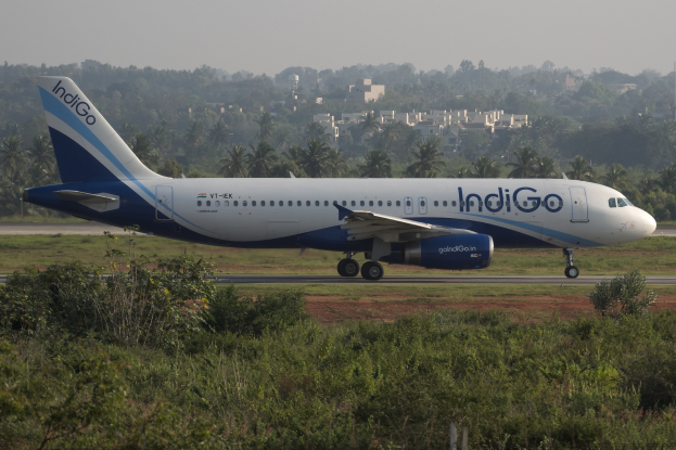Indigo Airlines Airbus A320-200 auf dem Mumbai Airport-Flughafen mit Grünfläche, Bäumen, Gebäuden und klarem blauem Himmel.