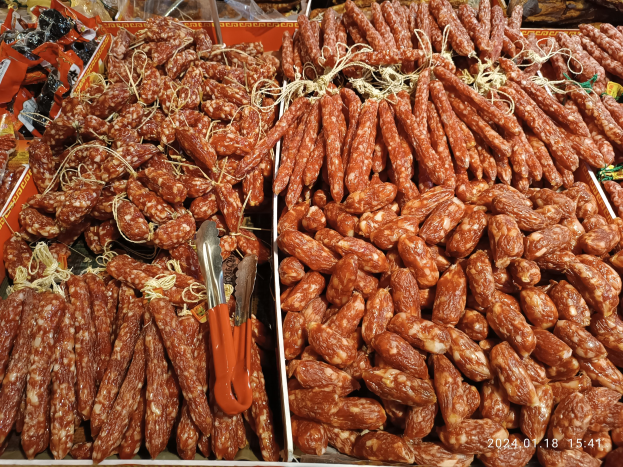 Vitrine gefüllt mit verschiedenen Wurstsorten und verpackten Lebensmitteln, mit einem Wasserzeichen-Overlay.