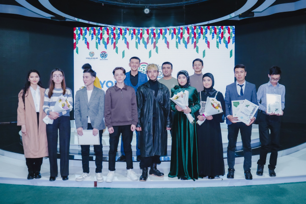 Gruppe von Menschen auf einer Bühne mit Blumensträußen und Urkunden, vor einem "Youth Solar Awards 2019"-Hintergrund.