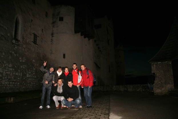 Menschen, die in der Mitte des Bildes mit einer Burg im Hintergrund bei Nacht stehen.
