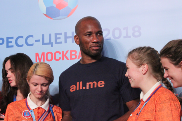 Eine Gruppe von Menschen mit Medaillen auf einer Bühne stehend, im Hintergrund ein Banner mit Text und einem Fußballbild, das ihre Teilnahme an der 2018 FIFA WM Russland anzeigt.