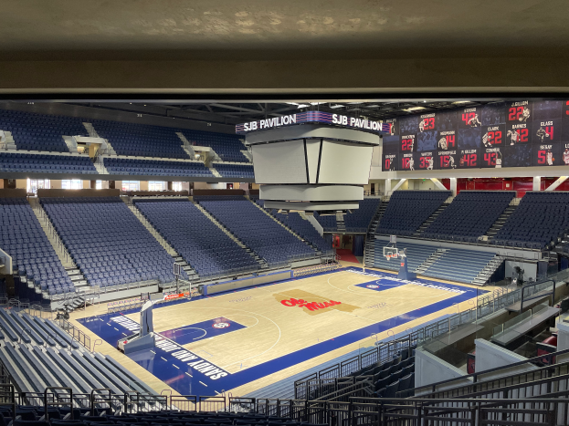 Eine große Halle mit einem Basketballfeld, Sitzplätzen und Anzeigetafeln, auf denen "SUB Pavilion an der University of Texas at Austin" steht.
